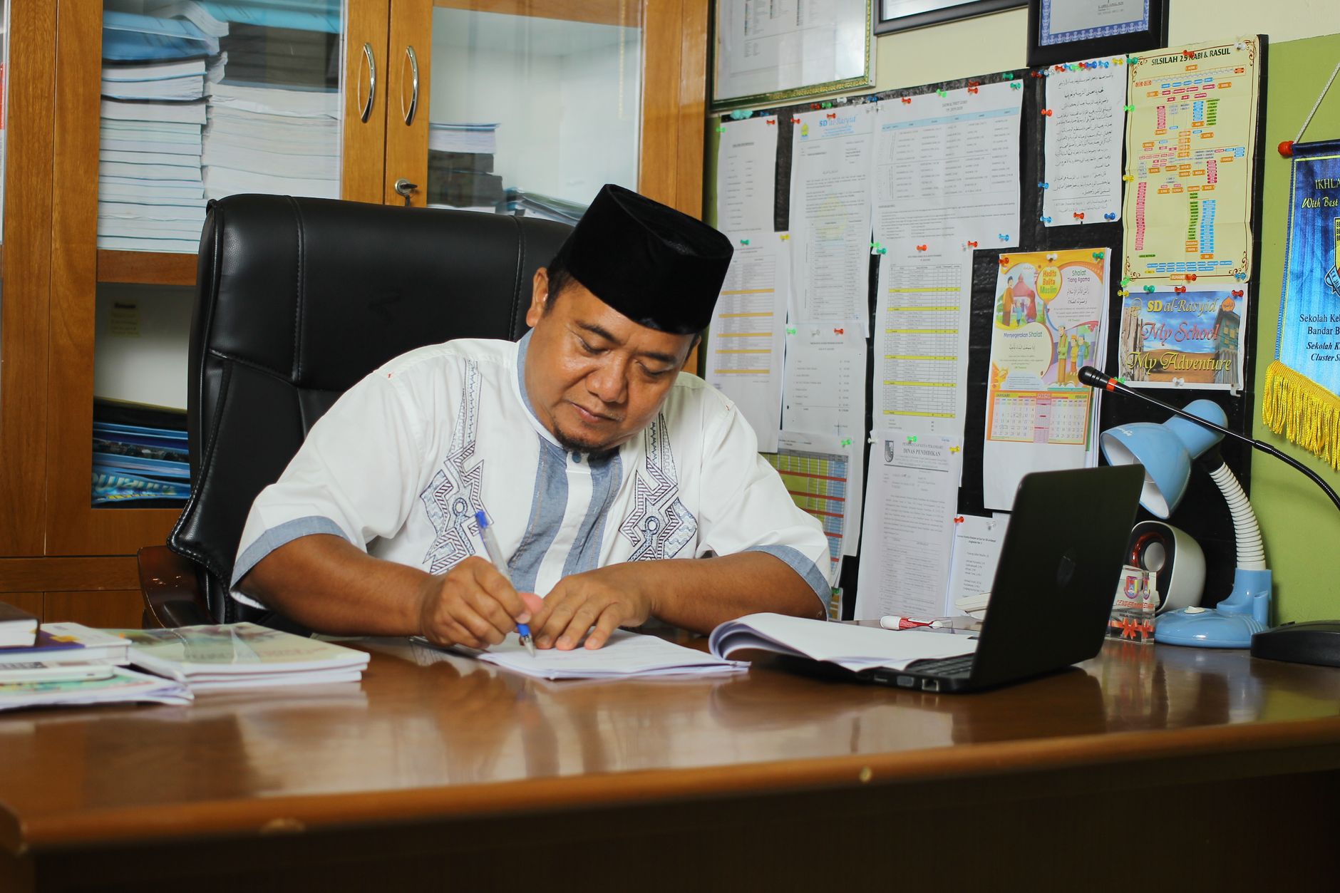 school principal filling out documents in his office