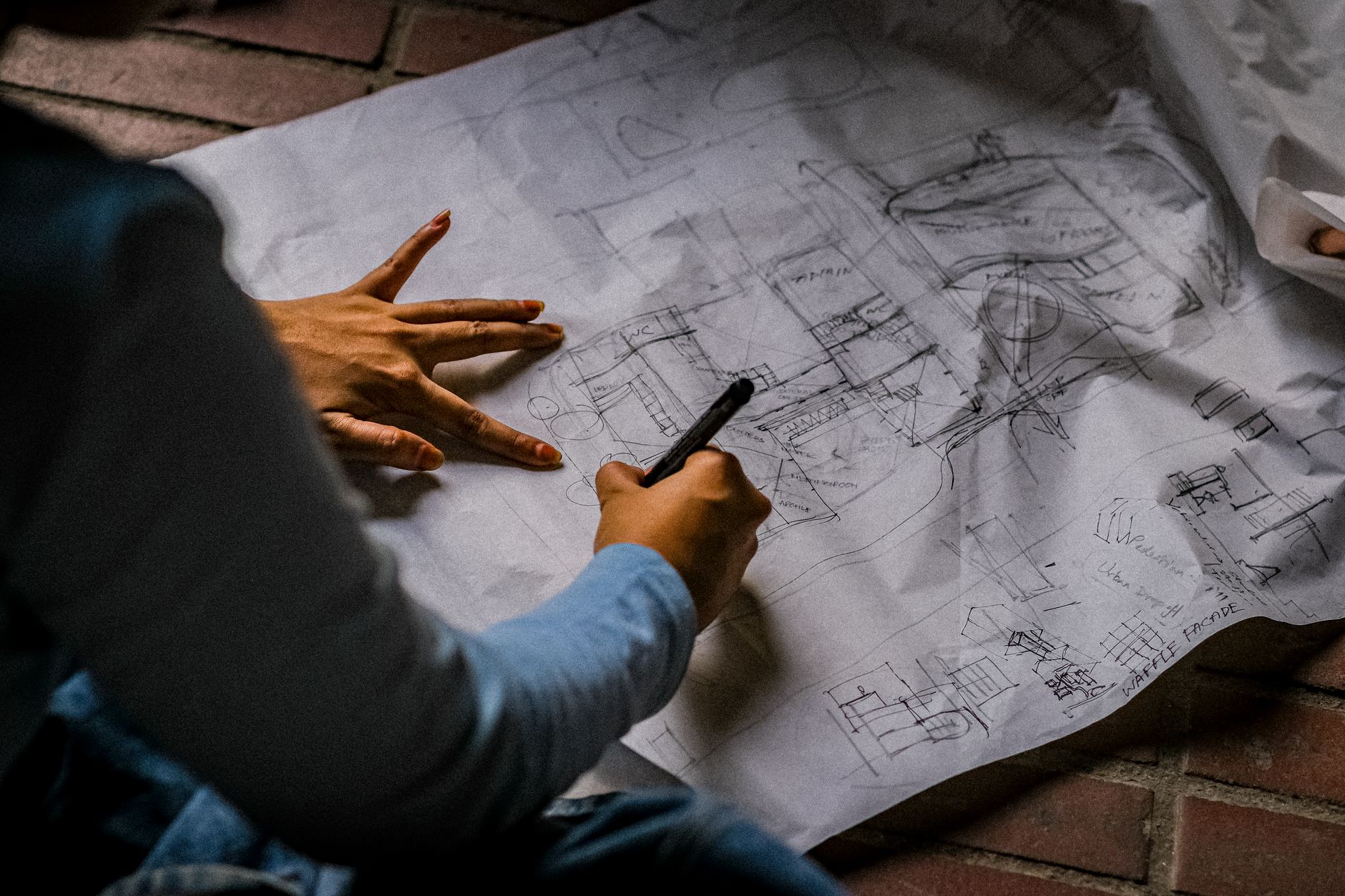 architect sketching blueprint on floor